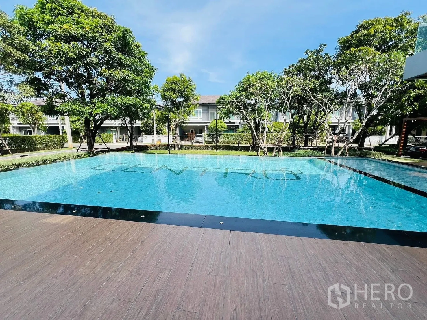 Detached House for rent in Prawet, Bangkok - Outdoor swimming pool surrounded by trees and low-rise houses.