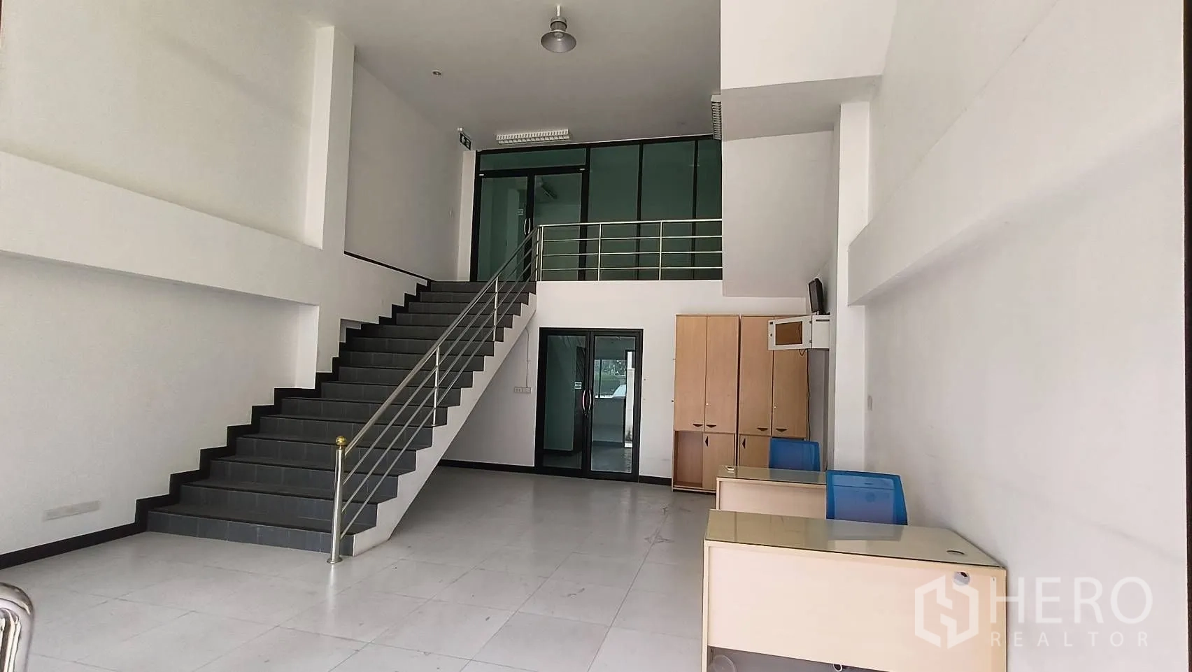 Office Space for rent in Khlong Toei, Bangkok - Showroom-style space with high ceiling, staircase and glass-partitioned office.