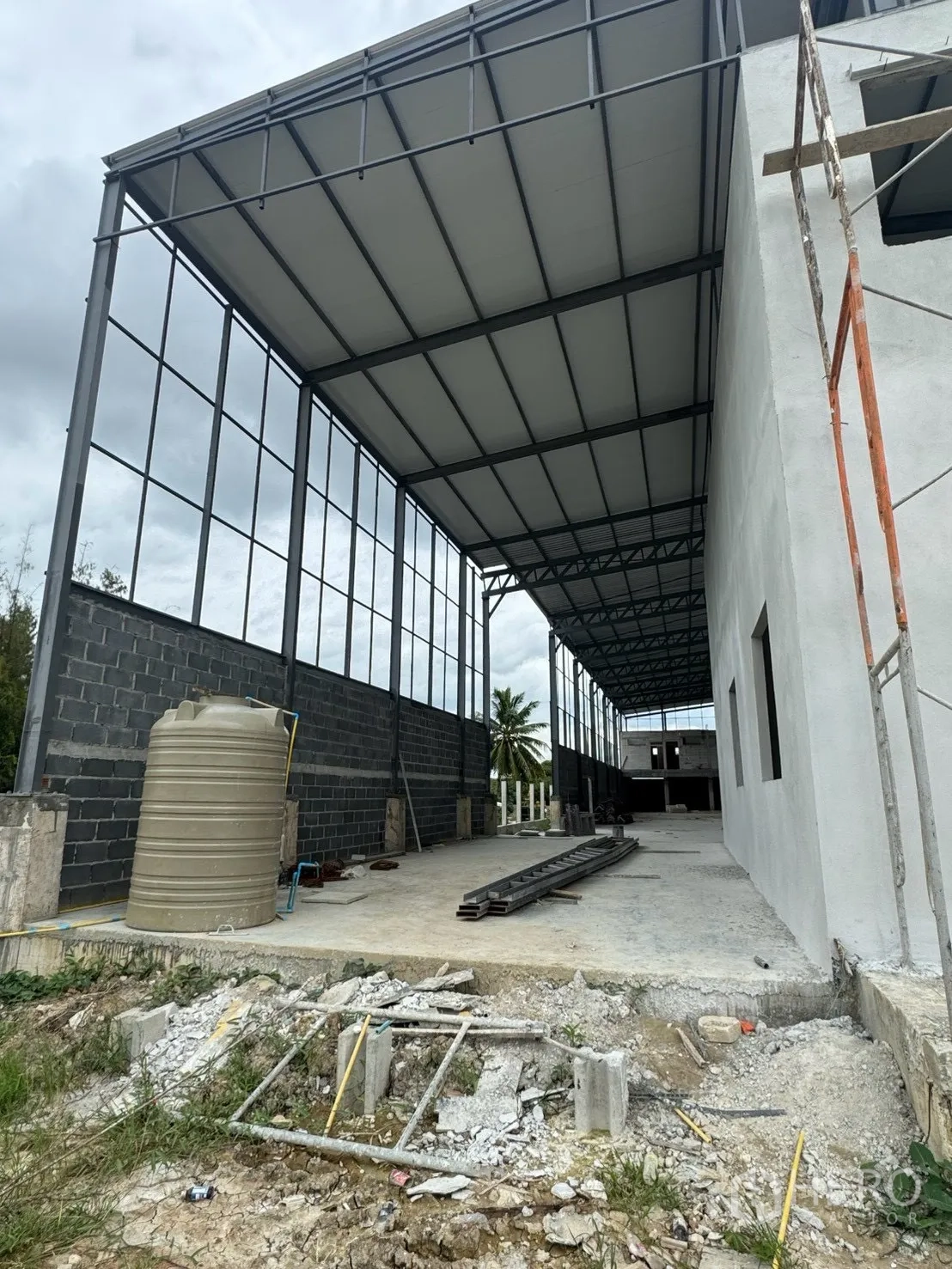 Factory for rent in Phutthamonthon, Nakhon Pathom - Covered side bay beside the building with water tank and open concrete apron.