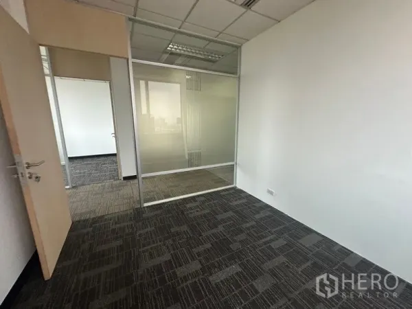 办公空间 出租在Khlong Toei, Bangkok - 小型办公室，磨砂玻璃隔断与格栅吊顶照明。