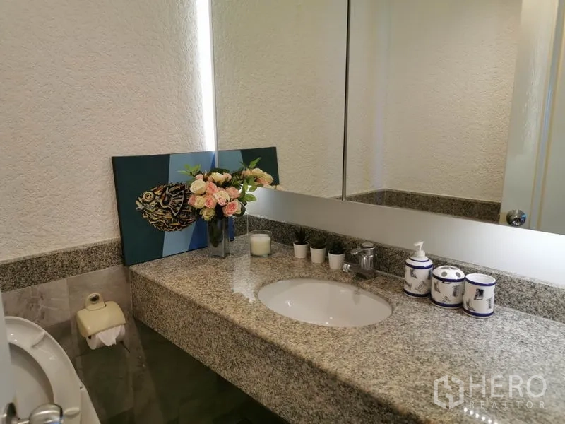 Condominium for rent in Watthana, Bangkok - Bathroom vanity with granite countertop, large mirror and decorative accents.