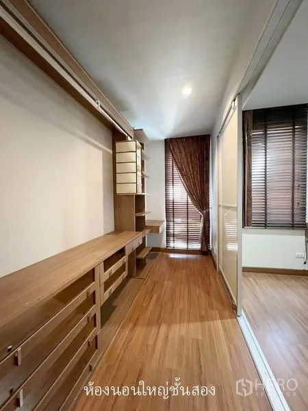 Townhouse for rent or sale in Don Mueang, Bangkok - Walk-in closet featuring custom wood cabinetry beside the bedroom.