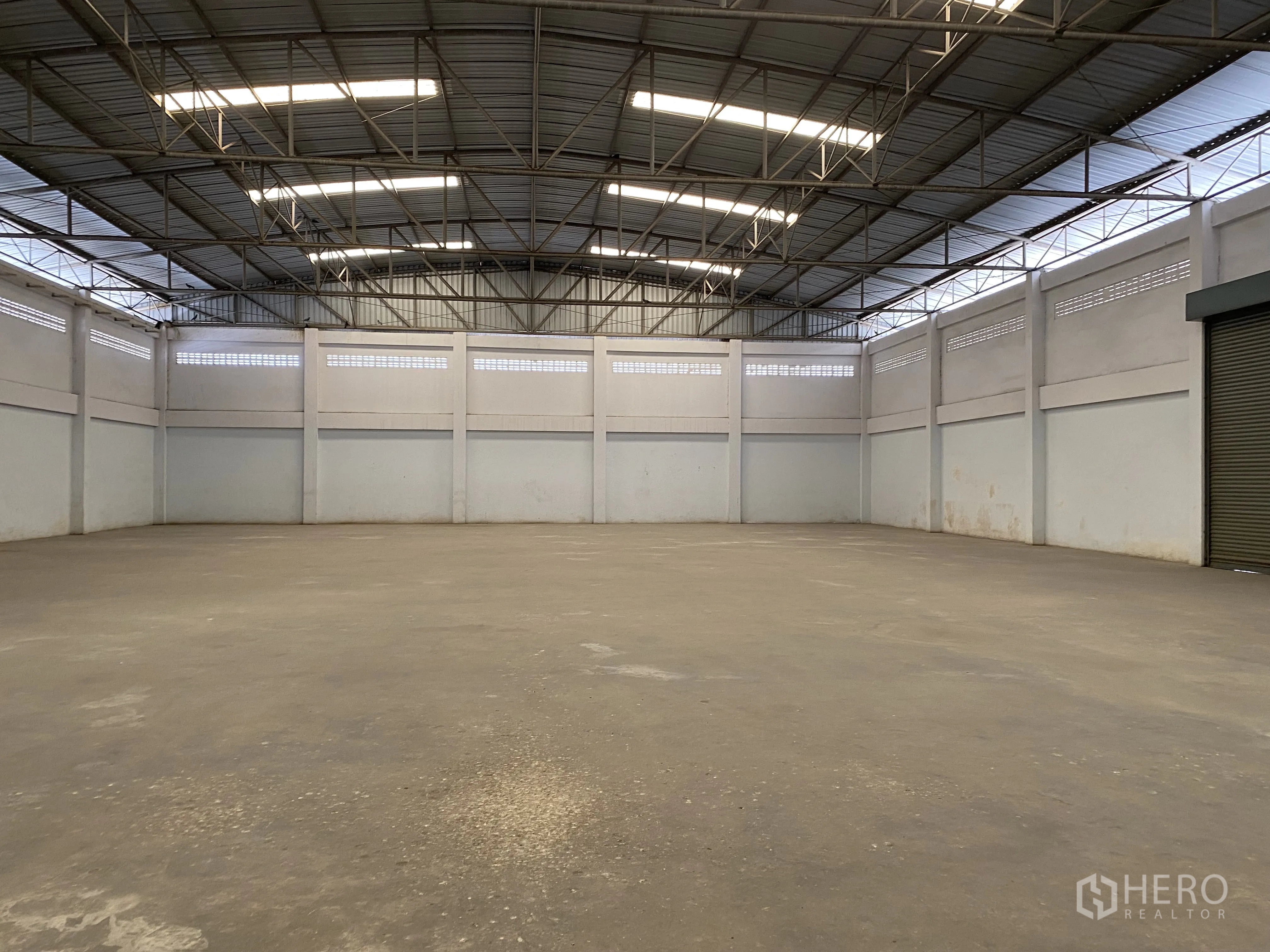 Factory for sale in Khlong Luang, Pathum Thani - Large warehouse interior with high steel truss roof and skylights.