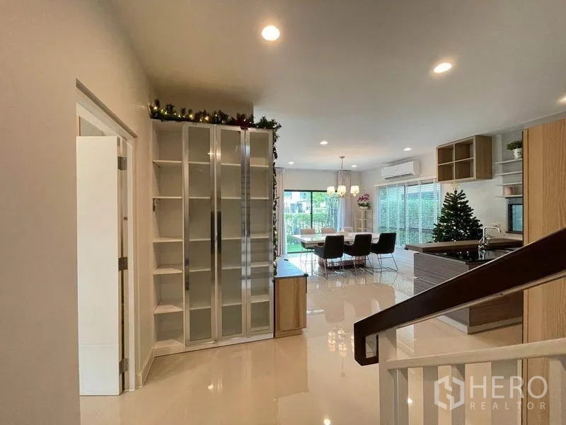 独立式住宅 出售在Pak Kret, Nonthaburi - 开放式餐厨区，亮面地砖、玻璃柜与通往花园的推拉门。