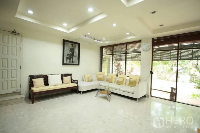 Detached House for rent in Bang Phli, Samut Prakan - Modern living room with recessed lighting, white sectional sofa and wide windows facing greenery.