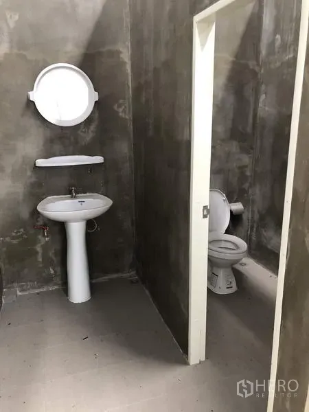 Warehouse for rent in Lat Lum Kaeo, Pathum Thani - Simple industrial restroom with pedestal sink, mirror and separate toilet cubicle.