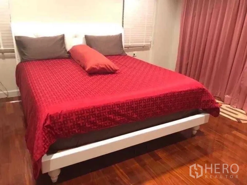 Detached House for sale in Saphan Sung, Bangkok - Cozy bedroom with double bed, red bedding, wooden flooring and soft lighting.