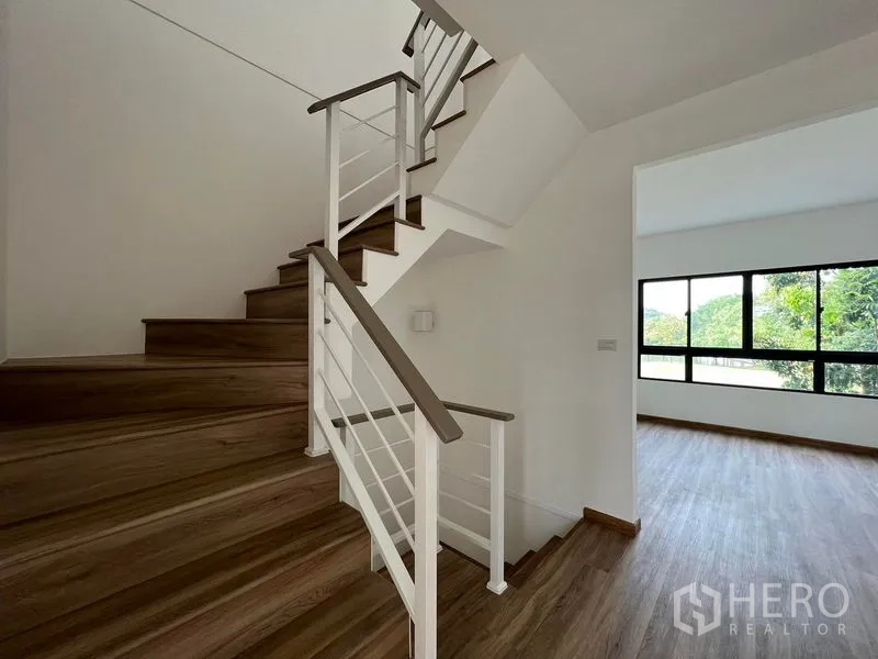 Townhouse for rent in Bang Kapi, Bangkok - Close view of modern staircase with white railing and wooden steps near the bedroom.