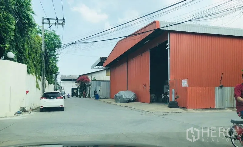货栈 出租在Bueng Kum, Bangkok - 街景：橙色金属外墙的仓库，入口宽敞，位于曼谷汶甘区的工业小巷。