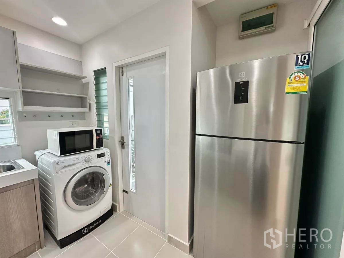Detached House for rent in Bang Phli, Samut Prakan - Utility corner with washing machine, microwave, stainless-steel fridge and open shelving.