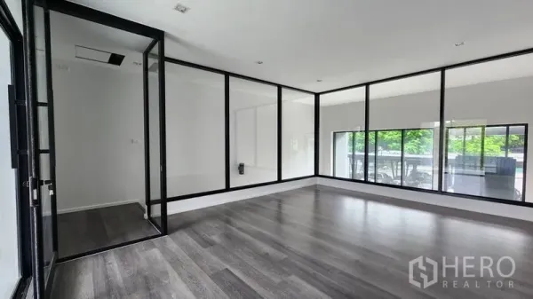 สำนักงานที่บ้าน ให้เช่า - ห้องทำงานโล่งพร้อมผนังกระจกกรอบดำและพื้นลามิเนตโทนไม้เข้ม