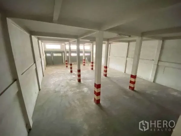 Warehouse for rent in Khlong Toei, Bangkok - Spacious warehouse hall seen from above with white walls, striped safety columns, and clerestory windows.