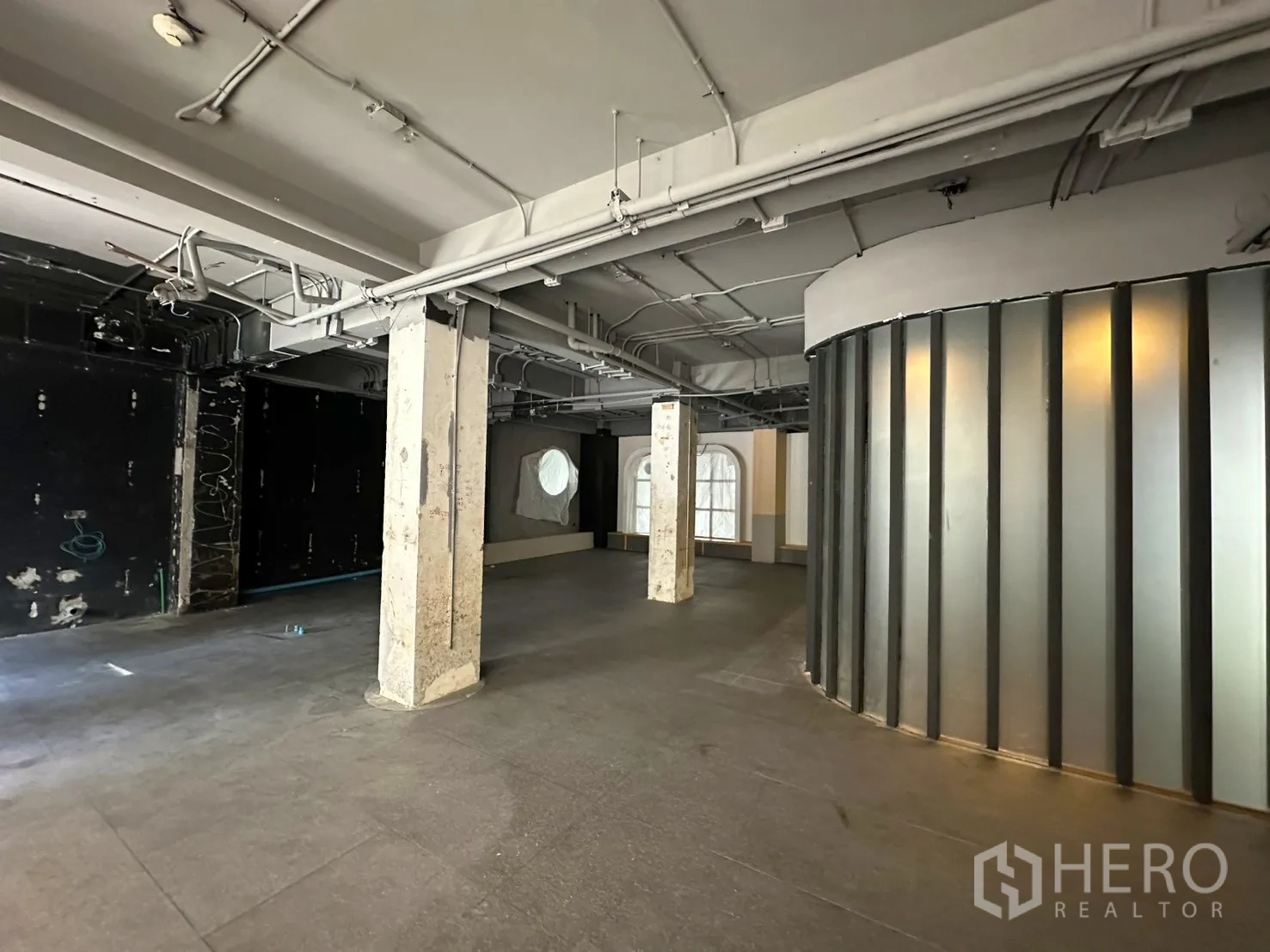 Retail Space for rent in Watthana, Bangkok - Retail shell showing a frosted curved partition, services ceiling, and wide unobstructed floor.