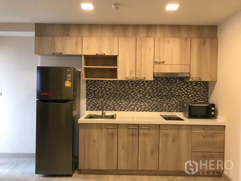 คอนโด ให้เช่าในWatthana, Bangkok - ครัวบิลท์อินตู้ไม้ ผนังกระเบื้องโมเสก เตาไฟฟ้า อ่างล้างจาน ไมโครเวฟ และตู้เย็น