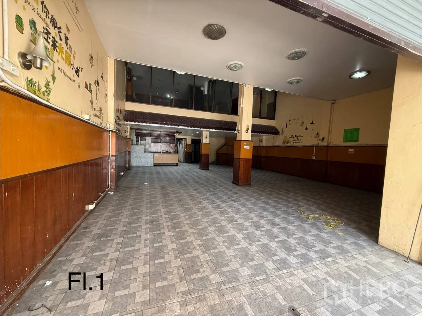 Shophouse for rent in Bang Na, Bangkok - Spacious ground-floor hall with high ceiling, tiled flooring, and wood wall panelling suited for retail or showroom use.