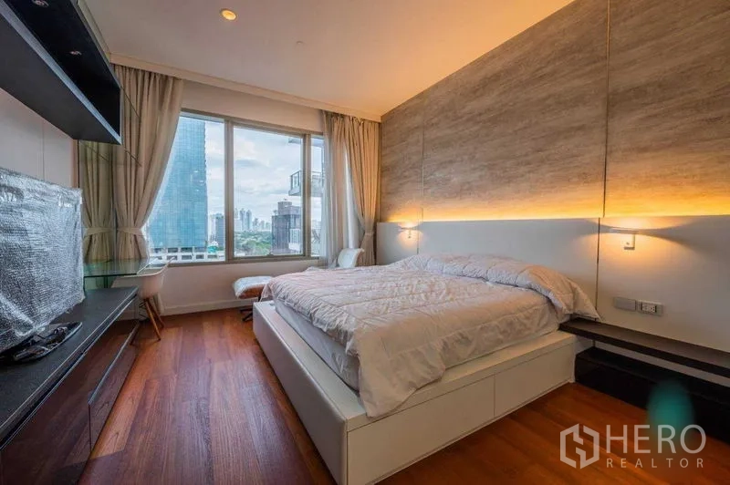 Condominium for rent in Pathum Wan, Bangkok - Bedroom with cove-lit headboard, large window, desk, and city view across Pathum Wan.