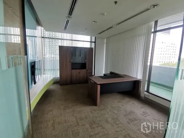 Office Space for rent in Bang Rak, Bangkok - Executive office with desk and cabinet, floor-to-ceiling windows and balcony access.
