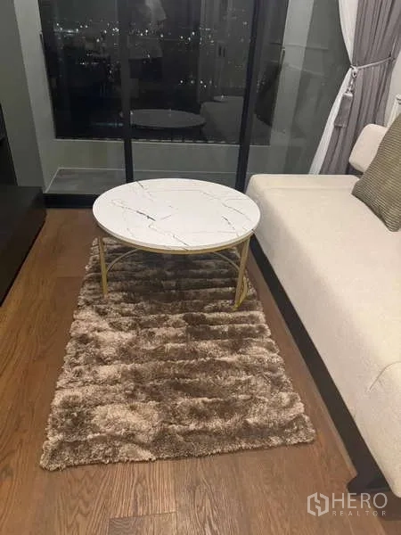 คอนโด ให้เช่าในKhlong Toei, Bangkok - โต๊ะกลางท็อปหินอ่อนทรงกลมบนพรมขนนุ่มข้างประตูกระจกระเบียง