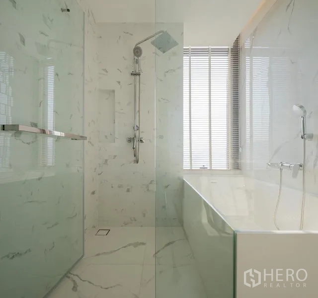 Condominium for rent in Khlong Toei, Bangkok - Luxury bathroom with separate glass shower and bathtub beside a window, finished in marble tile.