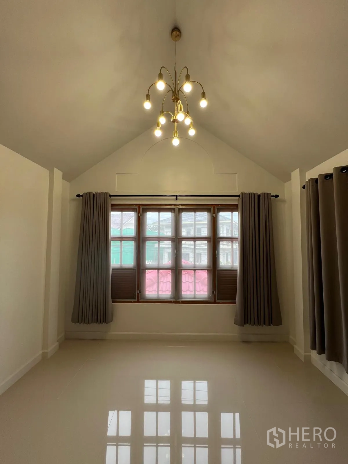 Detached House for rent in Saphan Sung, Bangkok - Bright room with vaulted ceiling, modern chandelier, large multi-pane window and gray curtains.