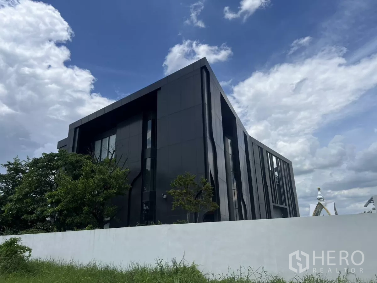 คลังสินค้า ขายในLat Krabang, Bangkok - มุมมองด้านหลังและด้านข้างของอาคารสีดำสมัยใหม่หลังกำแพงสีขาว.