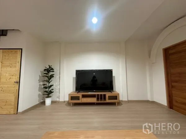 ทาวน์เฮาส์ ให้เช่าหรือขายในPhra Khanong, Bangkok - ผนังทีวีมินิมอล พร้อมจอใหญ่ ตู้วางทีวี และต้นไม้ในบ้าน