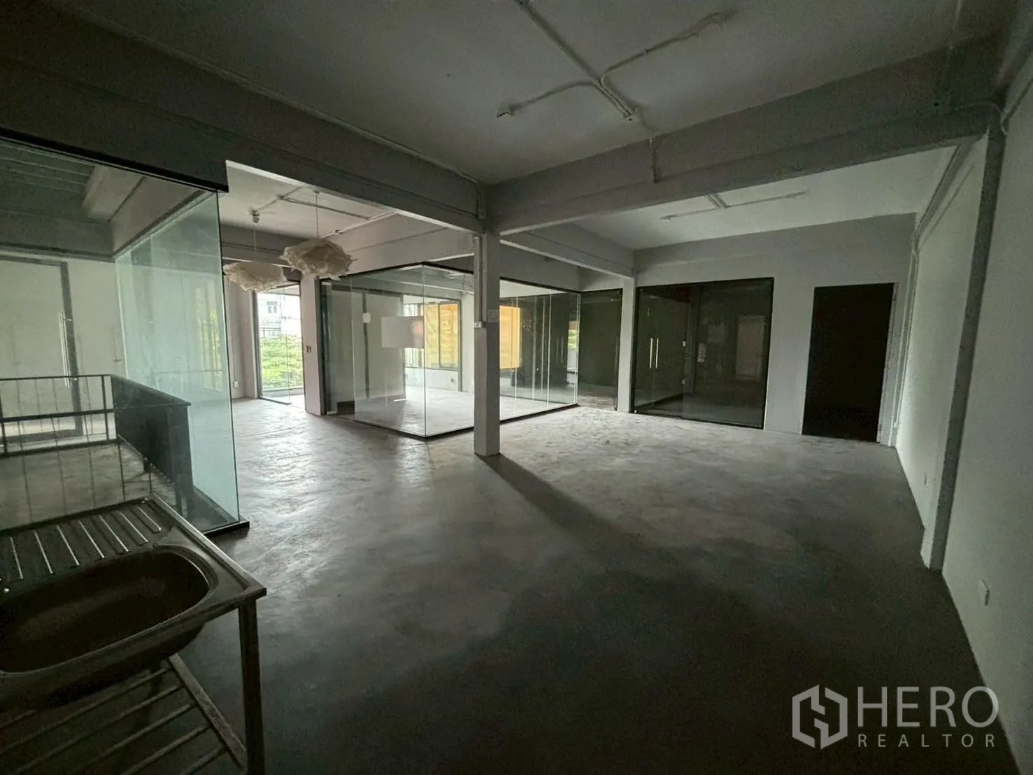 สำนักงาน ให้เช่า - พื้นที่ทำงานยืดหยุ่น พร้อมห้องกั้นกระจก โคมไฟแขวน และอ่างล้างอเนกประสงค์.