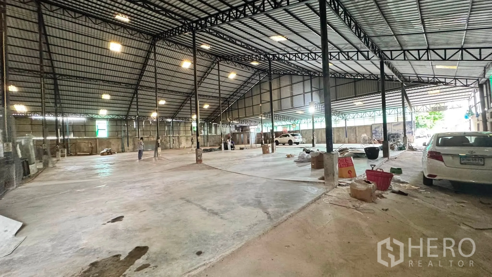 Warehouse for rent in Bang Khen, Bangkok - Wide warehouse floor with steel columns, parked vehicles, and work areas.