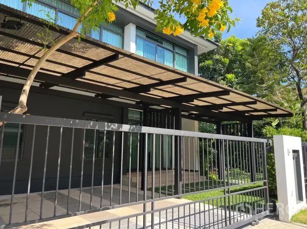 บ้าน ให้เช่าในBang Kapi, Bangkok - บ้านสองชั้นสไตล์โมเดิร์นพร้อมรั้วเหล็กและหลังคาที่จอดรถ รายล้อมด้วยต้นไม้