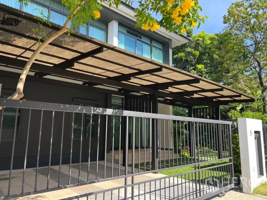 บ้าน ให้เช่าในBang Kapi, Bangkok - บ้านสองชั้นสไตล์โมเดิร์นพร้อมรั้วเหล็กและหลังคาที่จอดรถ รายล้อมด้วยต้นไม้