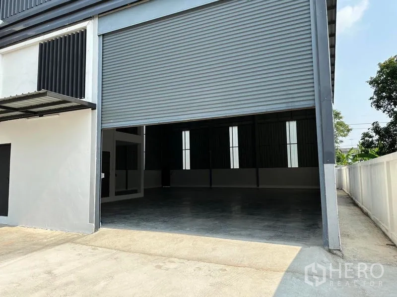 货栈 出租在Lam Luk Ka, Pathum Thani - 位于Lam Luk Ka的现代仓库外观，配大幅灰色卷闸门与混凝土装卸区
