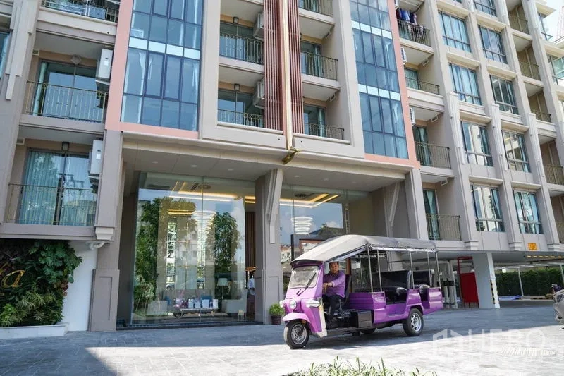 Condominium for sale in Huai Khwang, Bangkok - Modern condominium entrance and facade with glass lobby and tuk-tuk shuttle at Huai Khwang.