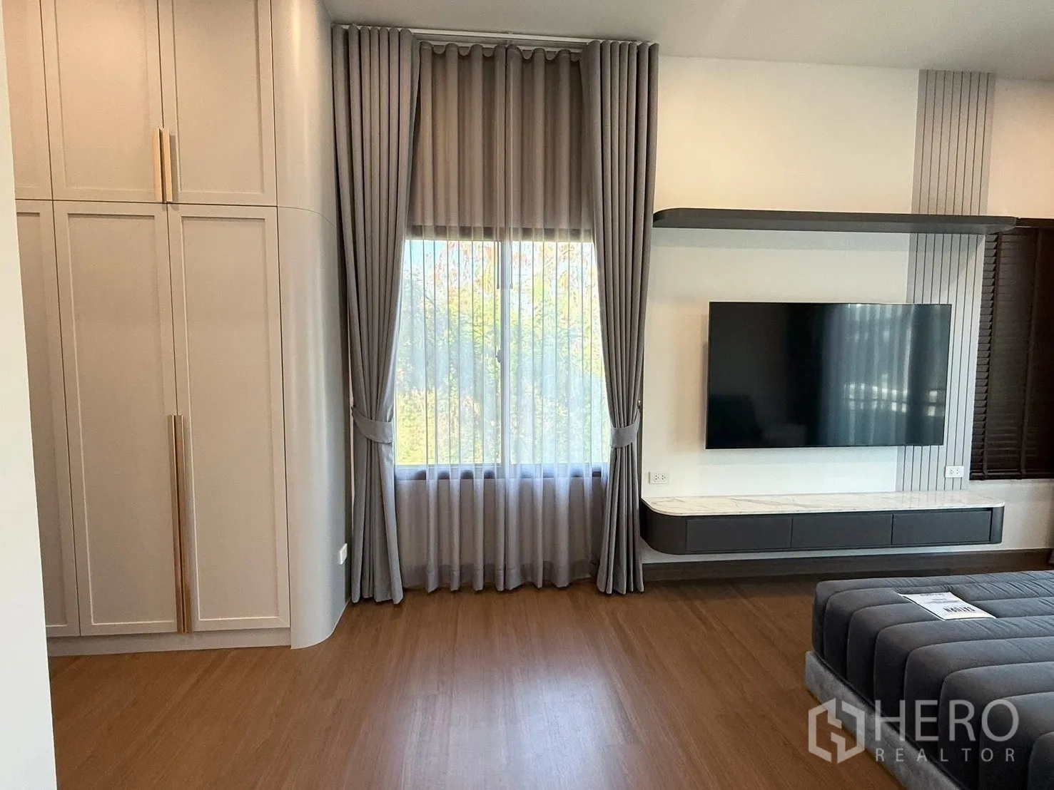 Detached House for rent in Bang Phli, Samut Prakan - Master bedroom area with large TV mounted on a feature wall and curtains.