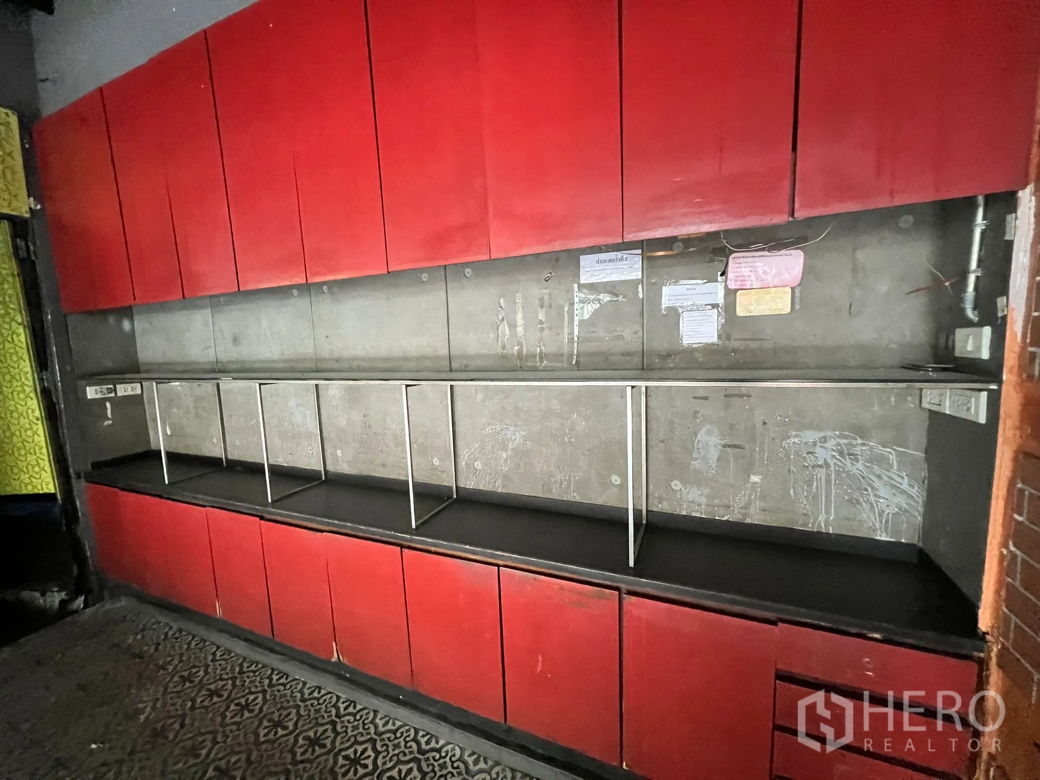 零售空间 出租在Watthana, Bangkok - 红色内置储物柜与开放展示层架，背靠水泥墙。