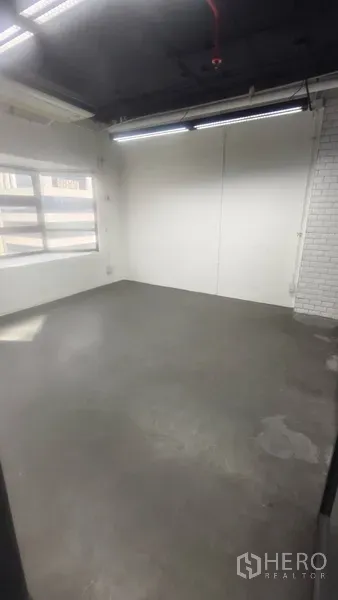 办公空间 出租在Pathum Wan, Bangkok - 角落办公间，水泥地、白色砖墙点缀与采光窗。