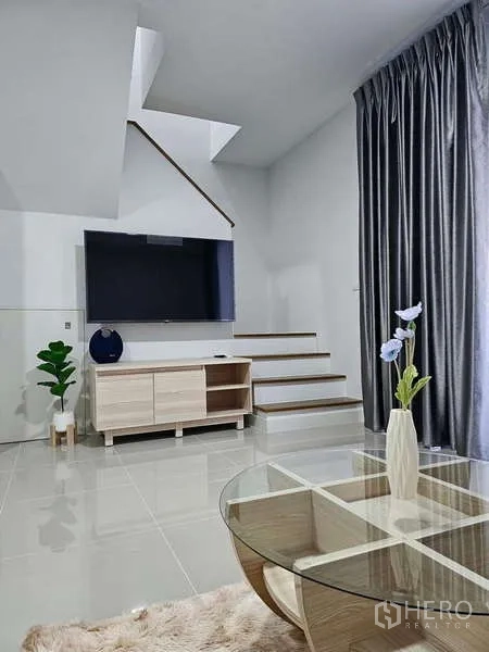 Townhouse for rent in Bang Phli, Samut Prakan - Living room with large TV, media console and staircase to the upper floor.