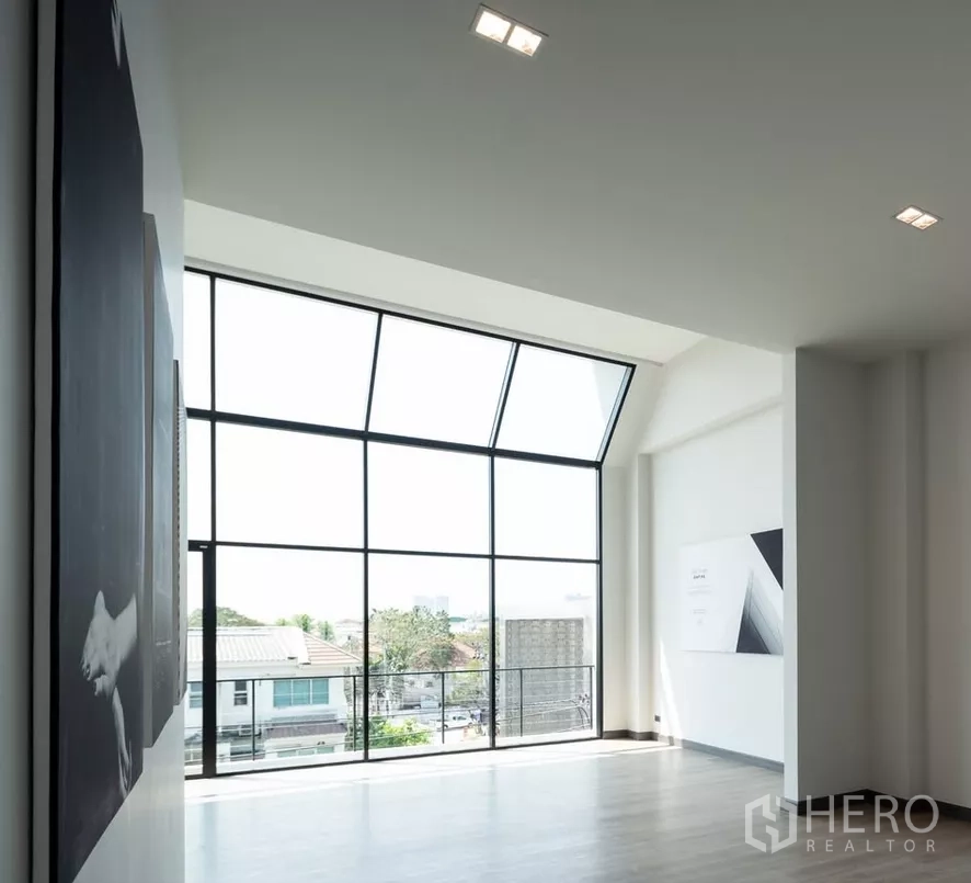 Home Office for sale in Bang Kapi, Bangkok - Sunlit room with full-height corner glazing and balcony views over the neighborhood.