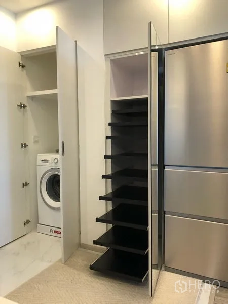 公寓 出租在Bang Na, Bangkok - 家政区展示不锈钢冰箱、可拉出式储物柜与柜中洗衣机。