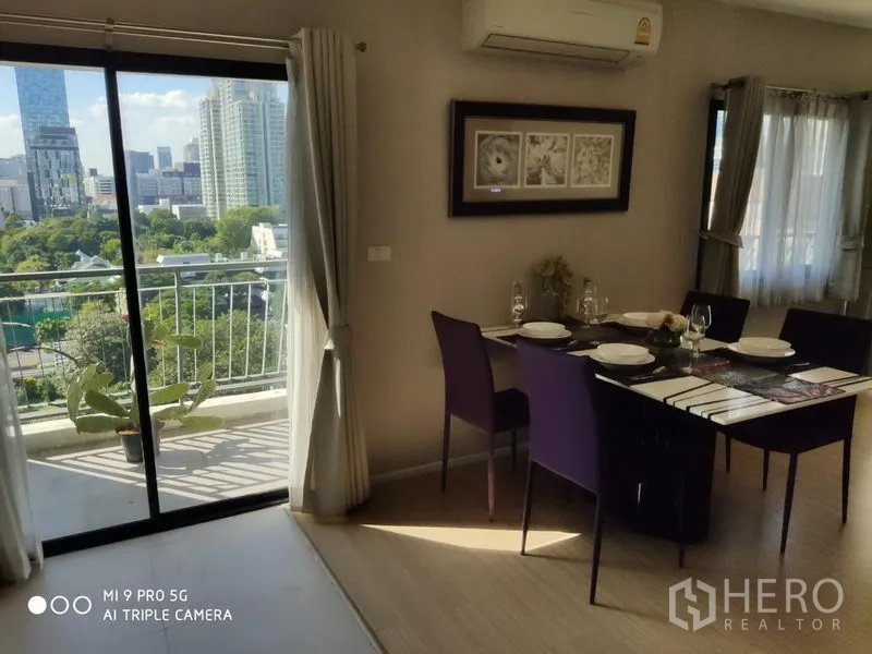 คอนโด ให้เช่าหรือขายในPathum Wan, Bangkok - มุมรับประทานอาหารสำหรับหกที่นั่ง ข้างประตูบานเลื่อนออกระเบียง มองเห็นวิวเมืองและพื้นที่สีเขียว