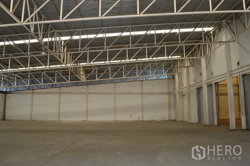 Warehouse for rent in Bang Sue, Bangkok - Steel truss ceiling spanning wide bays with service doors along the side wall inside the Bangkok warehouse.