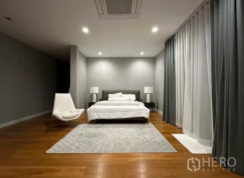 独立式住宅 出租 - 宽敞主卧，木地板与大地毯，床两侧设床头灯，整面窗帘.