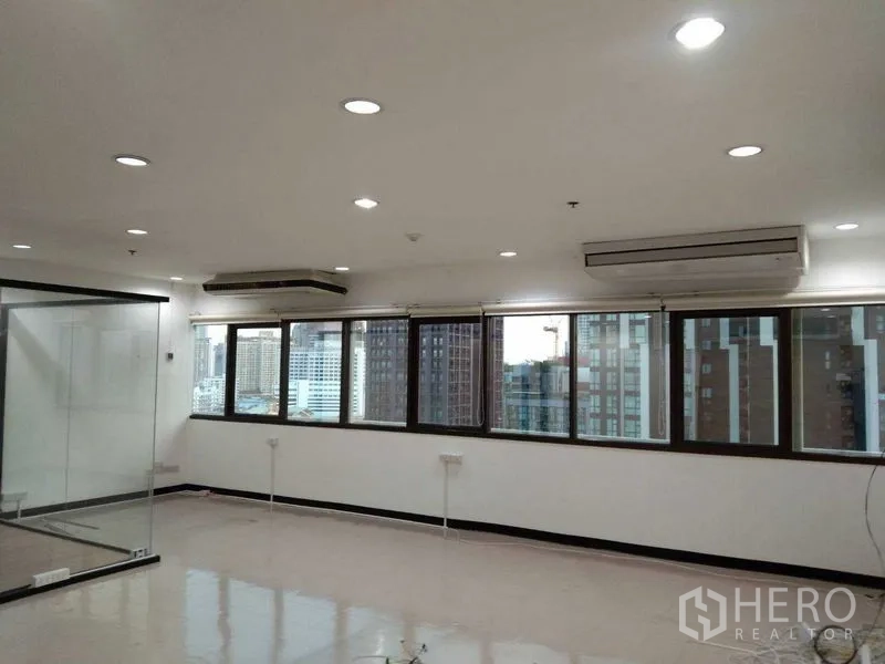 Office Space for rent in Watthana, Bangkok - Row of large windows with skyline views and wall-mounted air conditioners in a bright office.