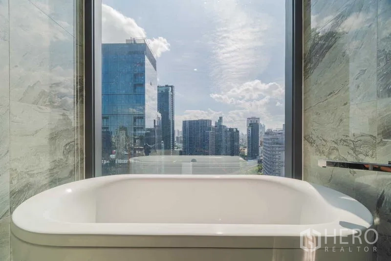 Condominium for rent or sale - Freestanding bathtub beside a full-height window overlooking the city skyline.