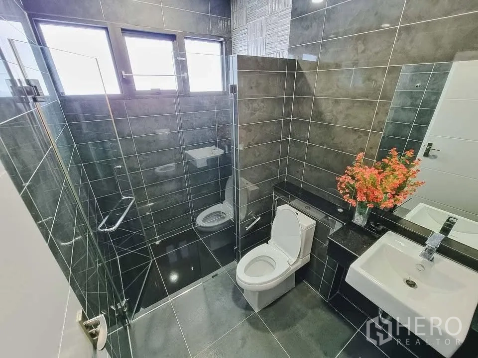 Detached House for rent or sale in Bang Phli, Samut Prakan - Bathroom with glass-enclosed shower, gray tiles, and modern fixtures.