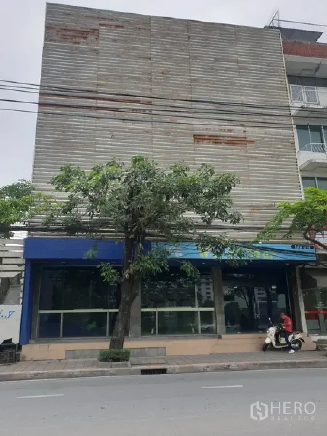 พื้นที่ขายปลีก ให้เช่าในWatthana, Bangkok - อาคารค้าปลีกติดถนน หน้าร้านกระจกเต็มแนว มีกันสีน้ำเงินและต้นไม้ริมทางเท้า