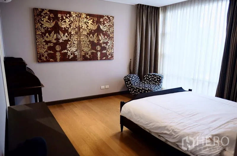 Condominium for rent in Watthana, Bangkok - Primary bedroom with wood floors, large window, drapes and wall art.