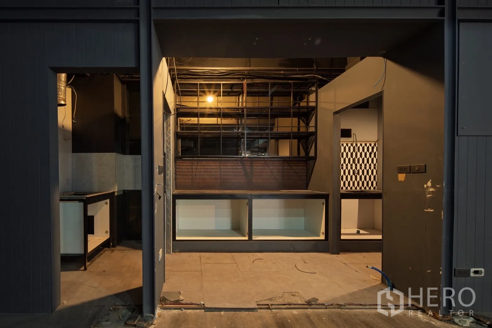 零售空间 出租在Watthana, Bangkok - 前场收银吧台与金属层架，后室为黑白方格墙面，待装修。