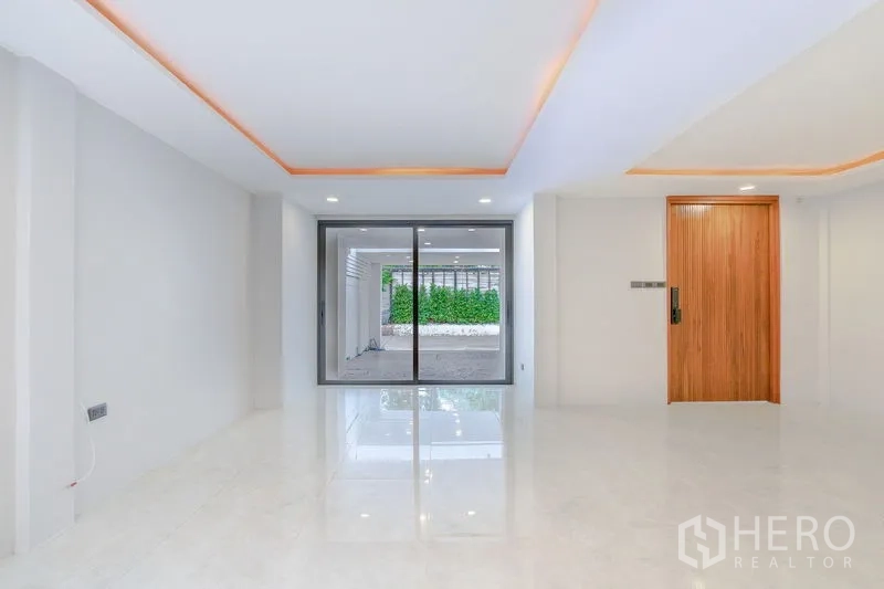 Townhouse for sale - Ground-floor living space with wood entrance door and glass sliders opening to the carport.