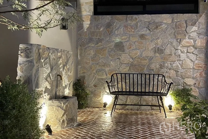 联排别墅 出售在Khlong Toei, Bangkok - 石材景墙配长椅与出水口，夜间灯光营造质感。