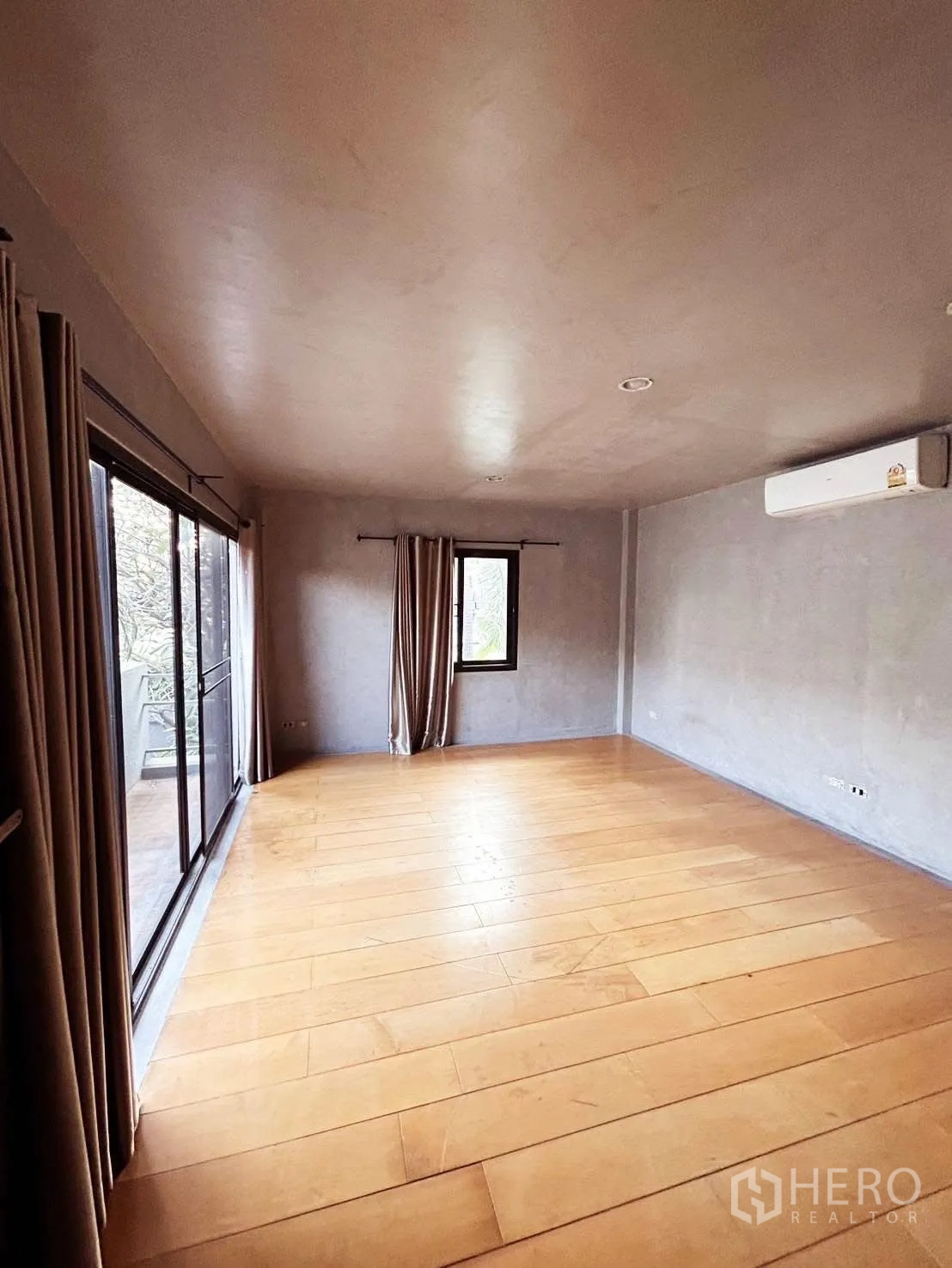 Detached House for rent or sale in Wang Thonglang, Bangkok - Large master bedroom with wide wooden floors, AC and balcony access via sliding doors.